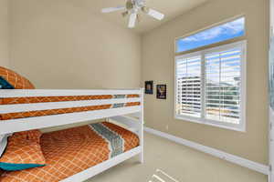 Carpeted bedroom featuring a ceiling fan, vaulted ceiling, and baseboards