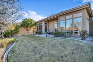 Rear view of property with a yard, a patio area, and stucco siding