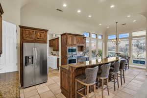 Kitchen with appliances with stainless steel finishes, light stone countertops, a towering ceiling, and washer and dryer