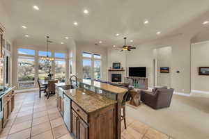 Kitchen featuring recessed lighting, a fireplace, a sink, stainless steel dishwasher, and a kitchen bar