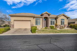 View of front facade featuring an attached garage, stone siding, concrete driveway, and stucco siding