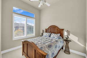 Bedroom featuring light carpet, ceiling fan, and baseboards