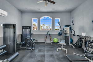 Gym with a wall unit AC and a ceiling fan