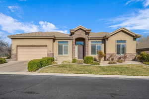 View of front of property featuring an attached garage, stone siding, and concrete driveway