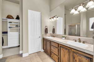 Bathroom with double vanity, a shower stall, a sink, and tile patterned floors