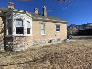 View of property exterior featuring brick siding, a mountain view, and a chimney