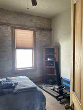 Bedroom featuring brick wall, carpet, and a ceiling fan