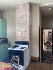 Kitchen with arched walkways, baseboards, electric stove, hardwood / wood-style floors, and stainless steel microwave