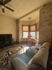 Living area with a textured ceiling, ceiling fan, wood finished floors, and baseboards