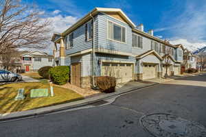 Multi unit property with stone siding, a chimney, an attached garage, and a residential view