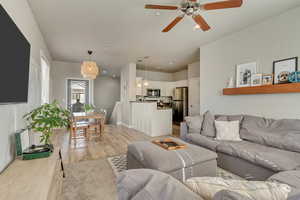 Living area featuring a ceiling fan, light wood-style flooring, and baseboards