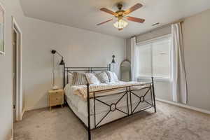 Bedroom featuring light carpet, baseboards, visible vents, and a ceiling fan