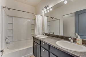 Full bathroom with shower / bath combo, a sink, and double vanity