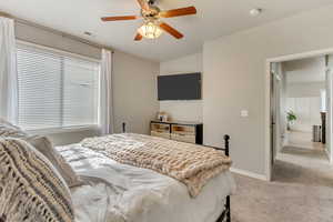 Bedroom with a ceiling fan, light colored carpet, visible vents, and baseboards