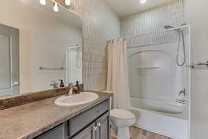 Full bathroom featuring toilet, shower / bath combo with shower curtain, wood finished floors, and vanity