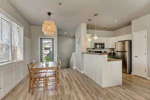 Kitchen with visible vents, white cabinets, appliances with stainless steel finishes, a peninsula, and light wood-type flooring