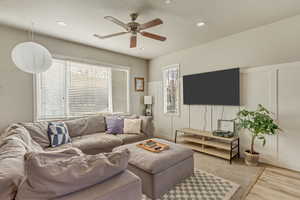 Living room with visible vents, ceiling fan, wood finished floors, a decorative wall, and recessed lighting