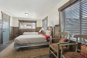 Bedroom featuring wainscoting, wood walls, and wood finished floors