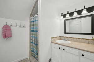 Bathroom with lofted ceiling, a shower with shower curtain, backsplash, and vanity