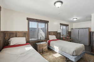 Bedroom featuring wood walls, multiple windows, and wainscoting