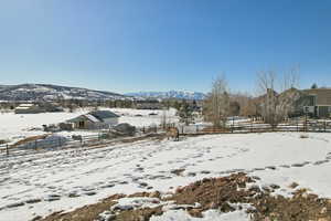 Yard layered in snow with fence and a mountain view