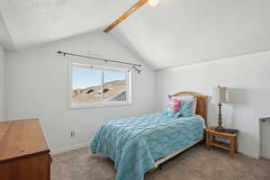 Bedroom with carpet, vaulted ceiling with beams, and baseboards