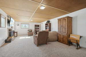 Living area featuring baseboards, a brick fireplace, and light colored carpet