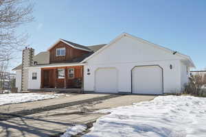 View of front of property with a garage, roof with shingles, driveway, and a chimney