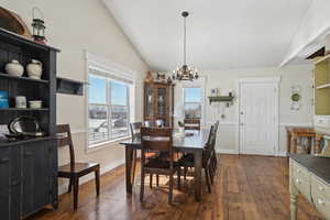 Dining space featuring vaulted ceiling, dark wood-type flooring, and plenty of natural light