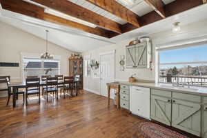 Kitchen featuring vaulted ceiling with beams, white dishwasher, a sink, green cabinets, and dark wood finished floors