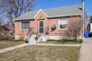 Bungalow with roof with shingles and brick siding