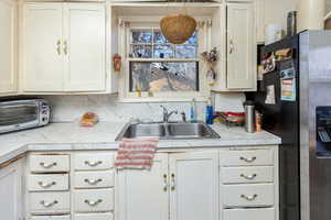 Kitchen featuring white cabinets, stainless steel fridge, a sink, and a toaster