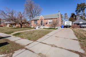 Bungalow with driveway, roof with shingles, a front lawn, and brick siding