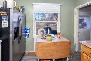 Kitchen with stainless steel refrigerator with ice dispenser, wood finished floors, and light countertops