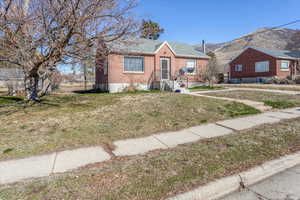 Bungalow-style house with a front yard, a mountain view, and brick siding