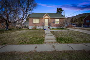 Bungalow-style home with brick siding, a mountain view, a front lawn, and roof with shingles