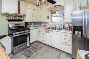 Kitchen featuring ceiling fan, appliances with stainless steel finishes, light countertops, light wood-style floors, and a sink