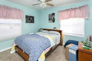 Bedroom with ceiling fan, a textured ceiling, baseboards, and carpet flooring