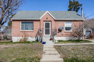 Bungalow-style home with entry steps, a shingled roof, and brick siding