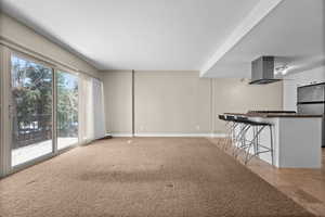 Unfurnished living room featuring light carpet and baseboards