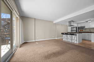 Unfurnished living room featuring light carpet, light tile patterned flooring, a sink, and baseboards