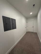 Hall with visible vents, carpet flooring, electric panel, and baseboards