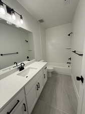 Full bath featuring toilet, vanity, visible vents, baseboards, and shower / bathing tub combination