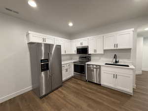 Kitchen featuring a sink, visible vents, white cabinetry, light countertops, and appliances with stainless steel finishes