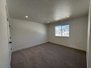 Unfurnished room with visible vents, a textured ceiling, dark carpet, a decorative wall, and recessed lighting