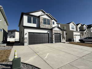 View of front of house featuring board and batten siding, a residential view, stone siding, and an attached garage