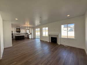 Unfurnished living room with dark wood-style floors, baseboards, a fireplace, and visible vents