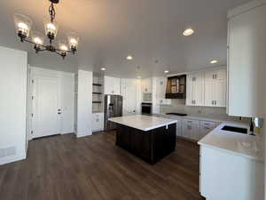 Kitchen with stainless steel appliances, premium range hood, visible vents, a center island, and open shelves