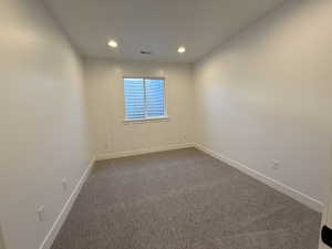 Spare room with recessed lighting, visible vents, dark carpet, and baseboards