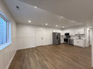 Kitchen featuring dark wood finished floors, visible vents, stainless steel appliances, and a sink